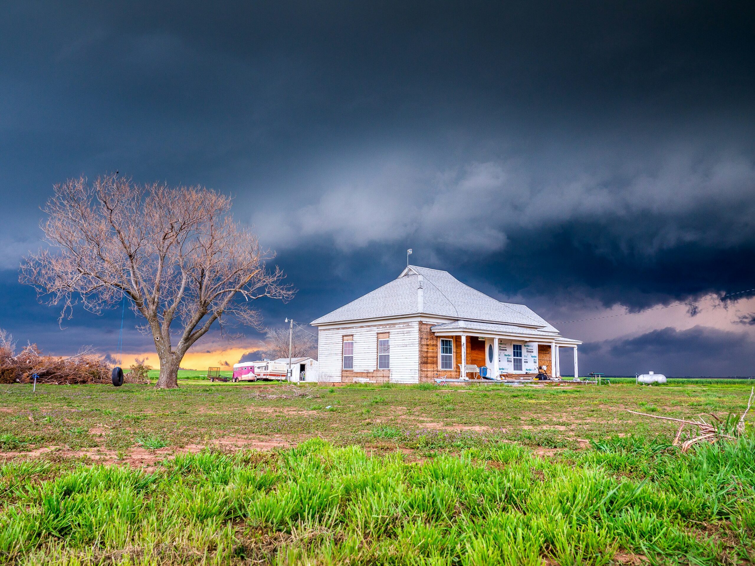 Winter-Proofing Your Roof in Tulsa: A white house with a grey roof in the midwest in front of a dark cloud front.