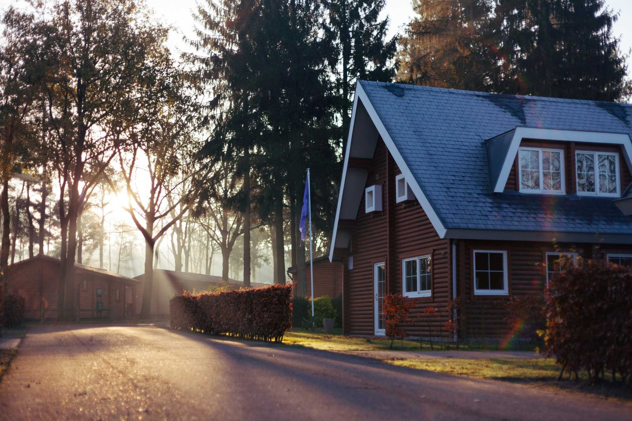 Emergency Roof Repairs in Tulsa: A family house in Oklahoma stands in front of a small forest. Sun is shining through the leafs of the tree.